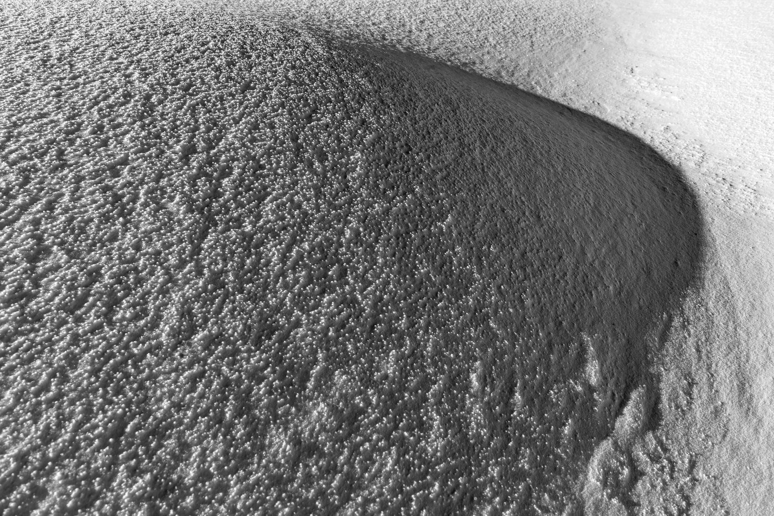 Fotografia invernale in bianco e nero, dettaglio della trama della neve lavorata dal vento
