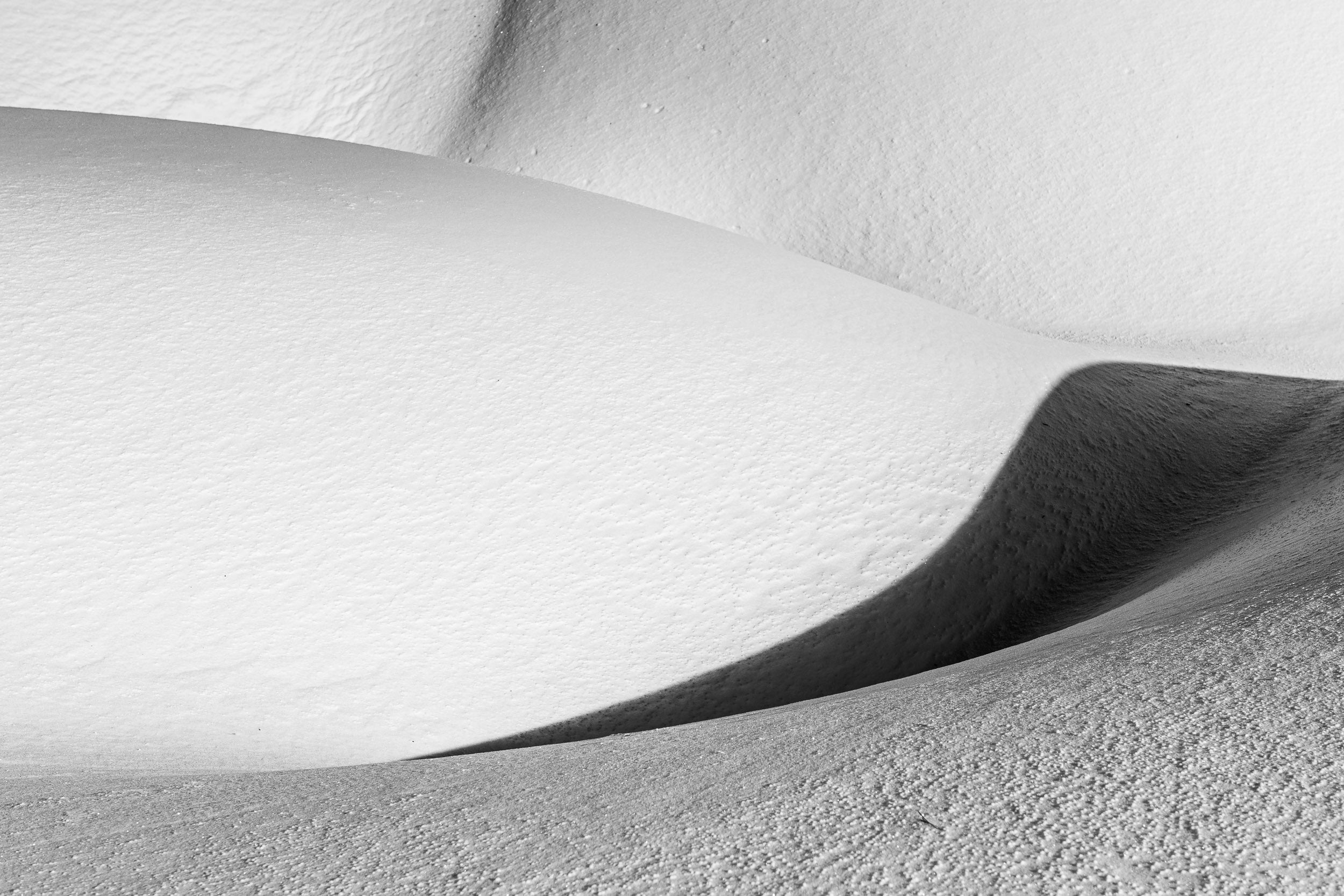 Fotografia in bianco e nero con sinuose e morbide forme create dalla neve come un opera astratta