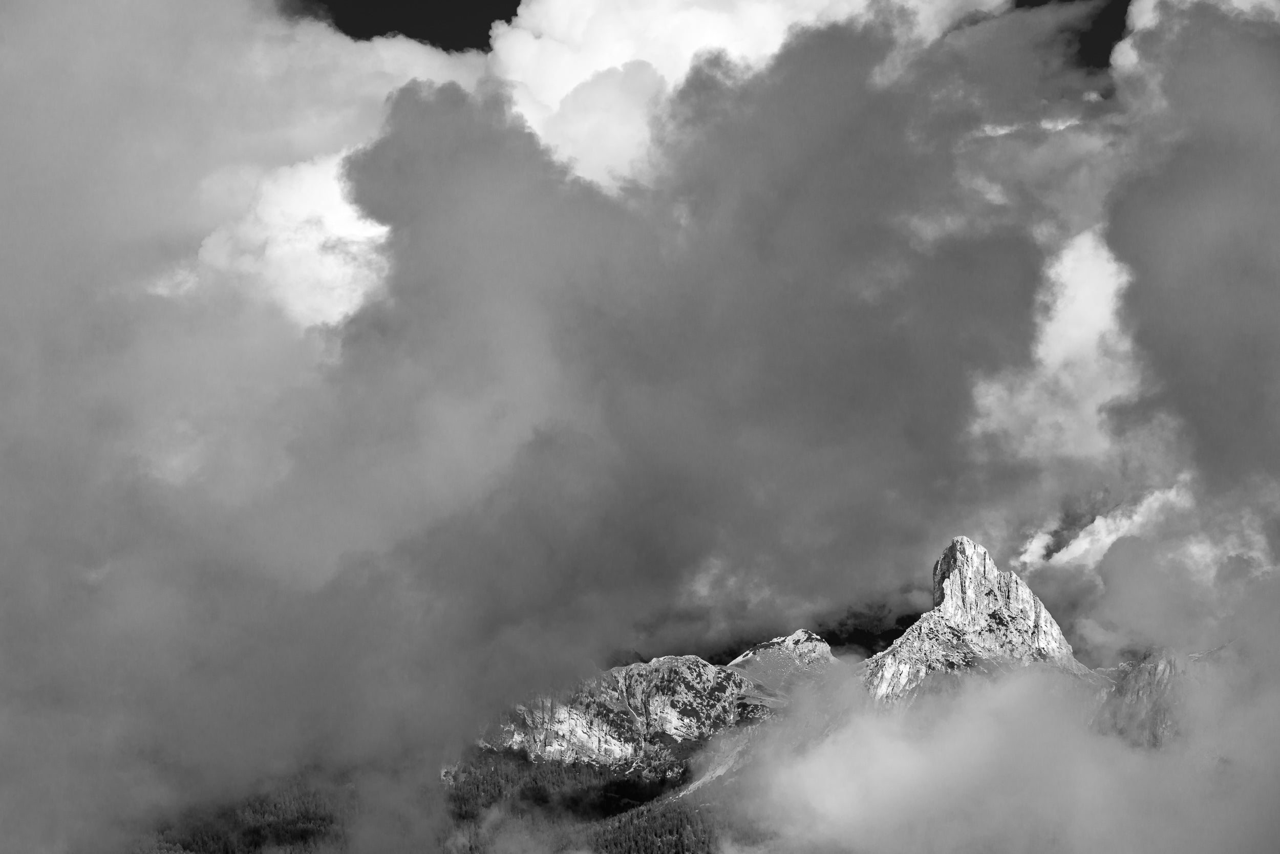 Fotografia in bianco e nero del Sass de Stria illuminato dal sole e circondato da nubi e nebbie