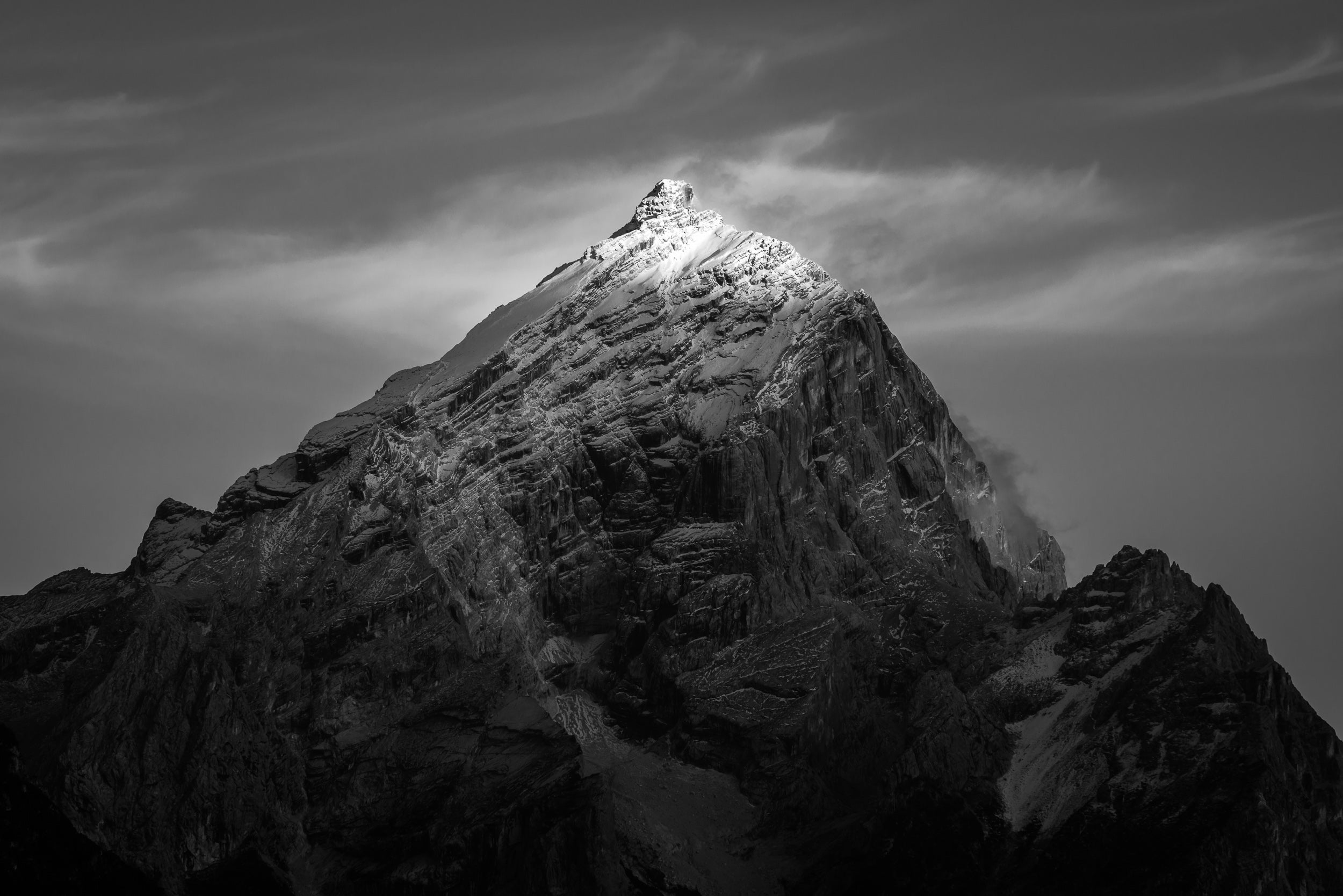 Fotografia in bianco e nero del Monte Antelao al tramonto in autunno, i raggi di sole illuminano solo al cima innevata.