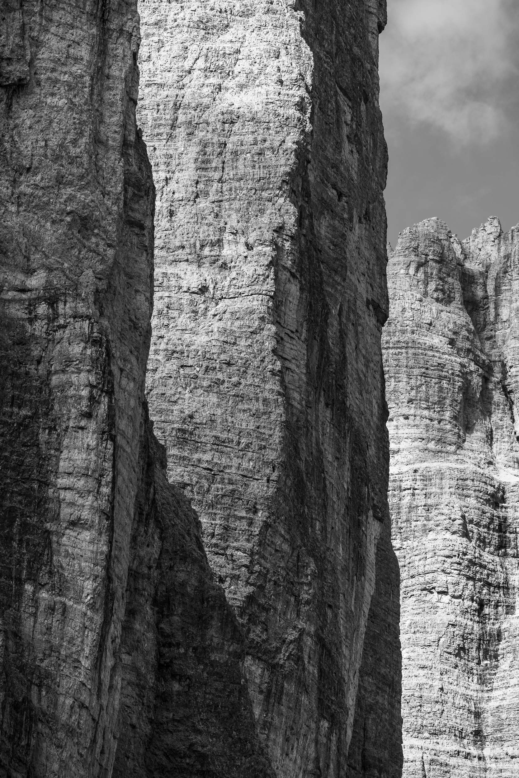 Fotografia verticale in bianco e nero con dettaglio sullo Spigolo Dibona, una via di arrampicata sulle Tre Cime di Lavaredo. Sono visibili diverse cordate di alpinisti