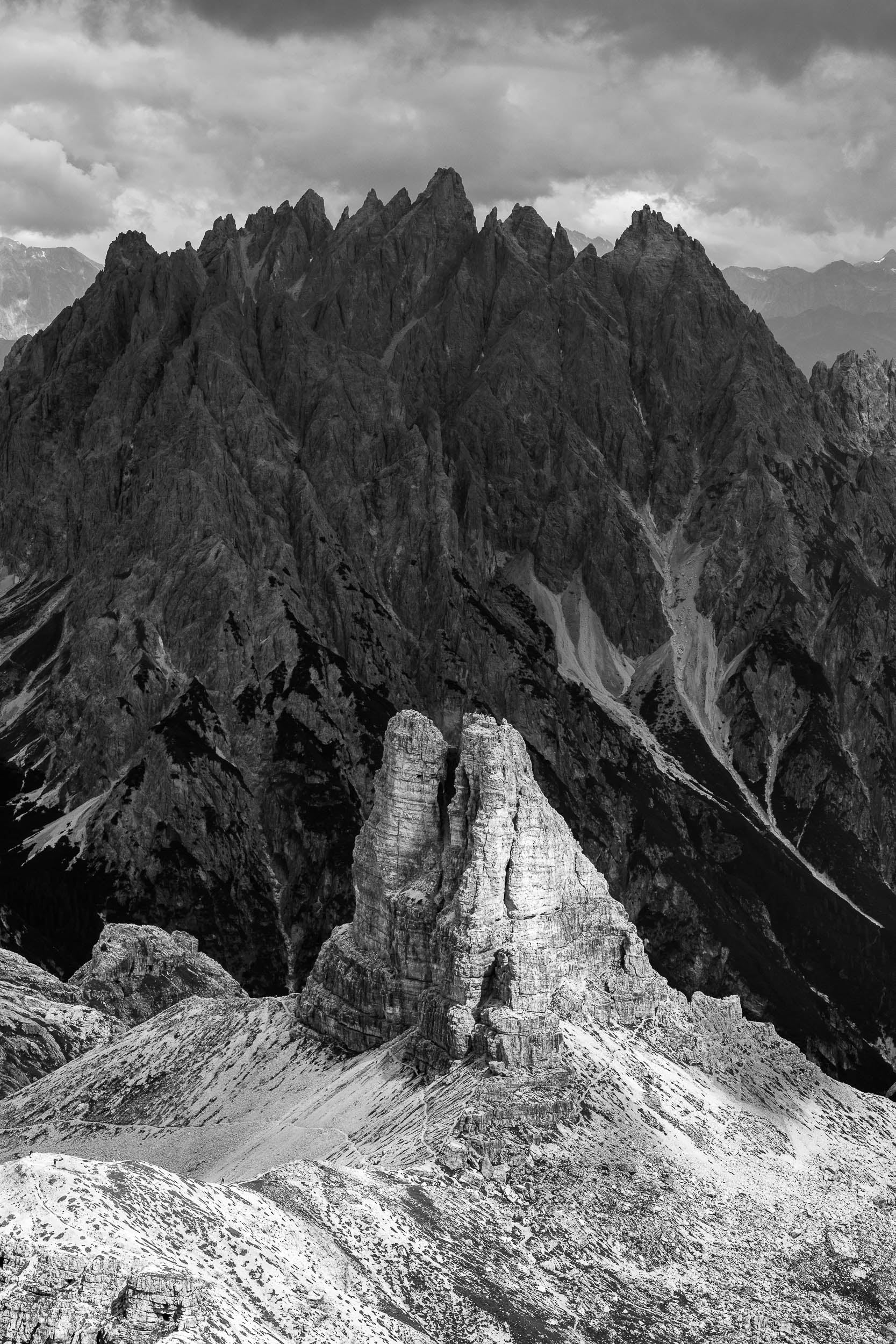Fotografia verticale in bianco e nero, in primo piano al sole la Torre di Toblin, sullo sfondo in ombra il Monte Baranci, Dolomiti di Sesto.
