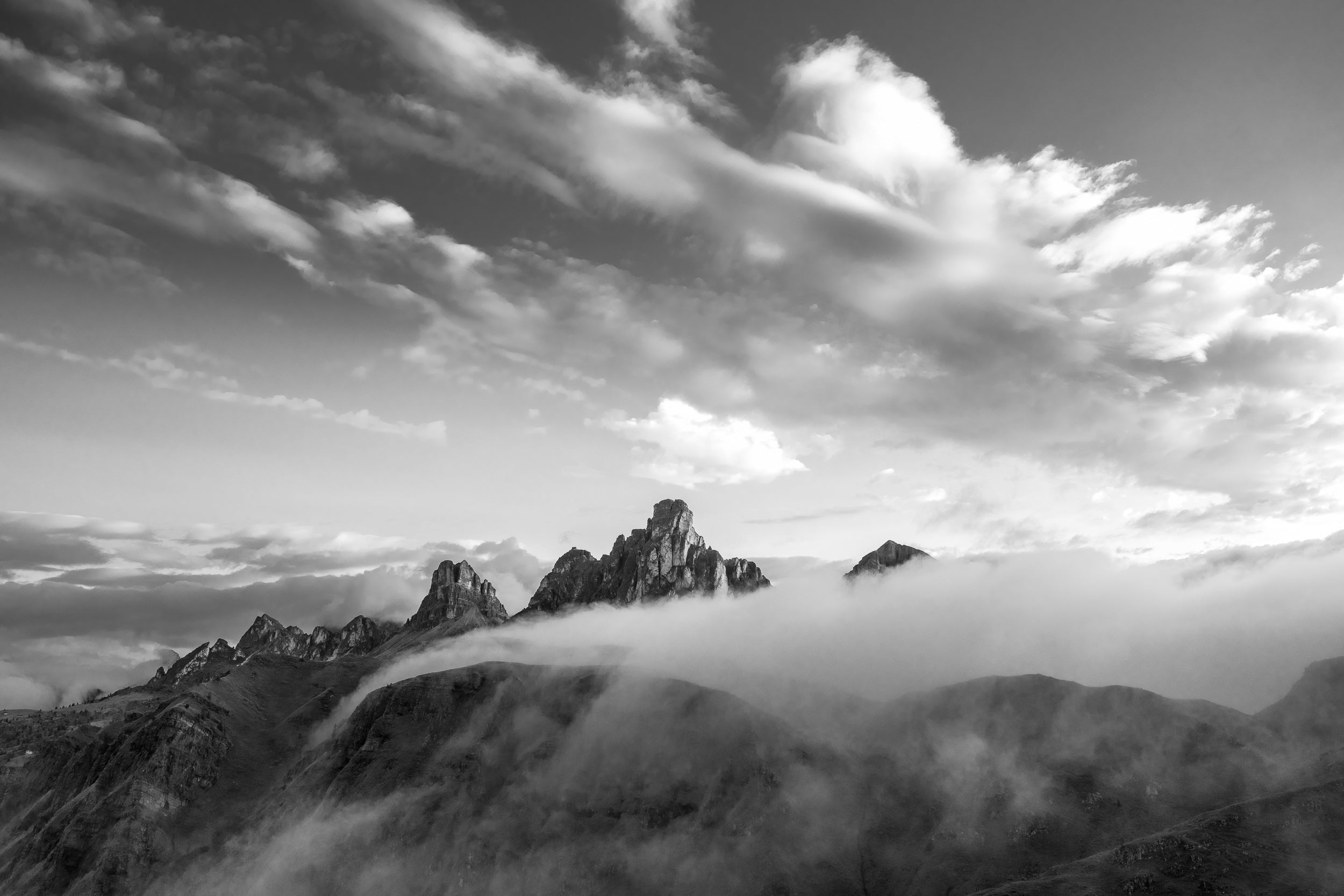 Fotografia in bianco e nero con cime dolomitiche che emergono dalle nebbie mattutine al Passo Giau