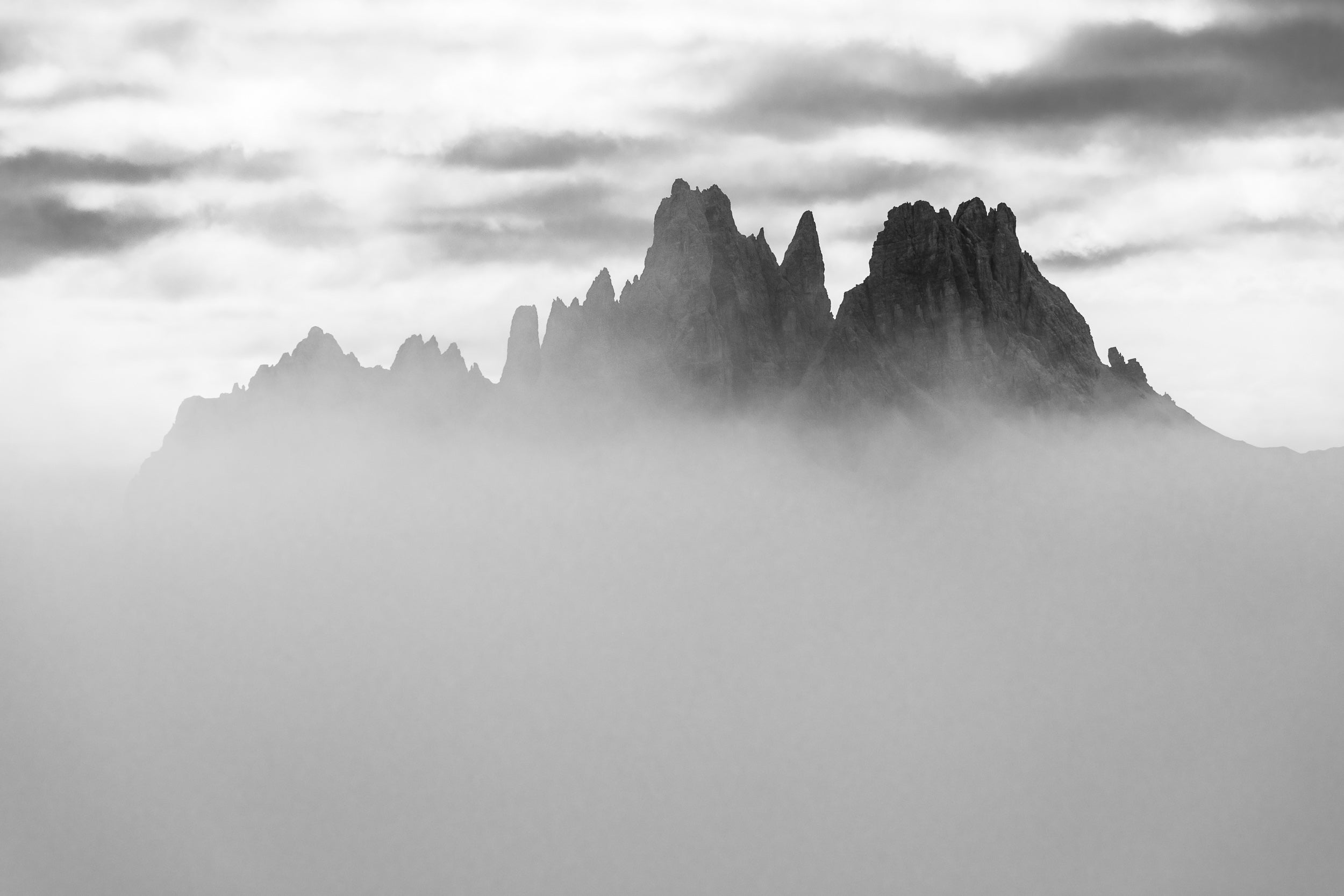 Fotografia in bianco e nero della Croda da Lago che emerge da un mare di nebbia